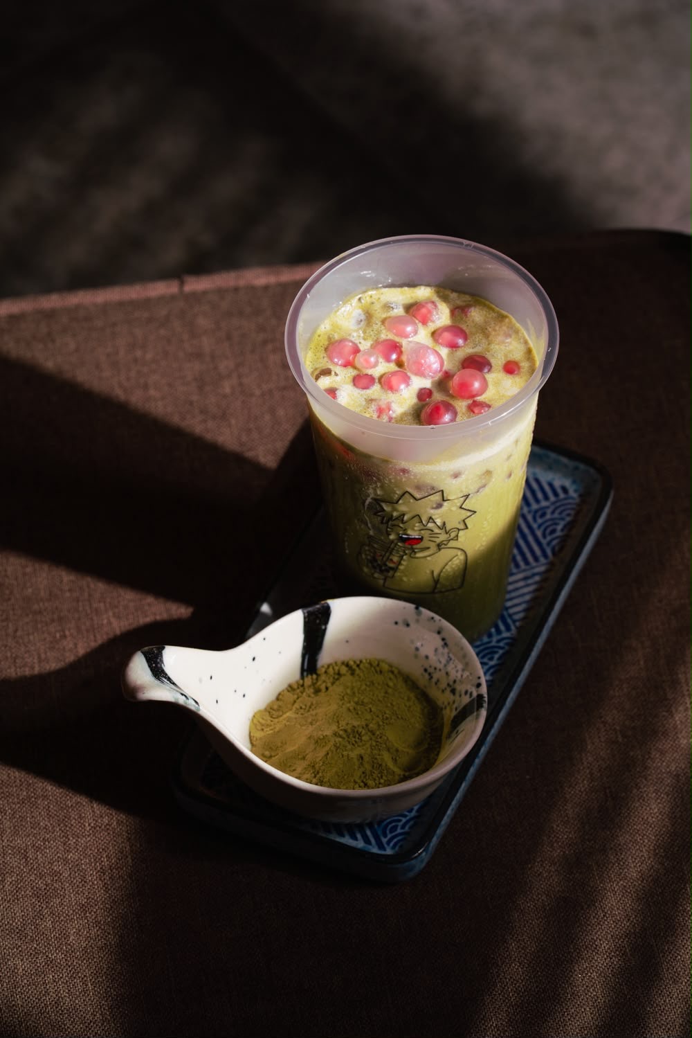 Matcha bubble tea served beside a bowl of matcha powder