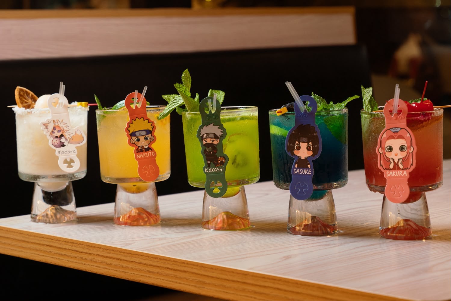 Five anime-themed cocktails lined up on the bar at Naruto SXM