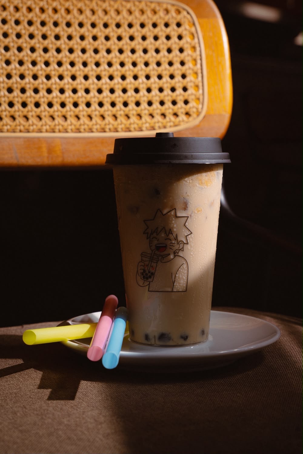 Iced milk bubble tea in a Naruto-printed cup in warm sunlight