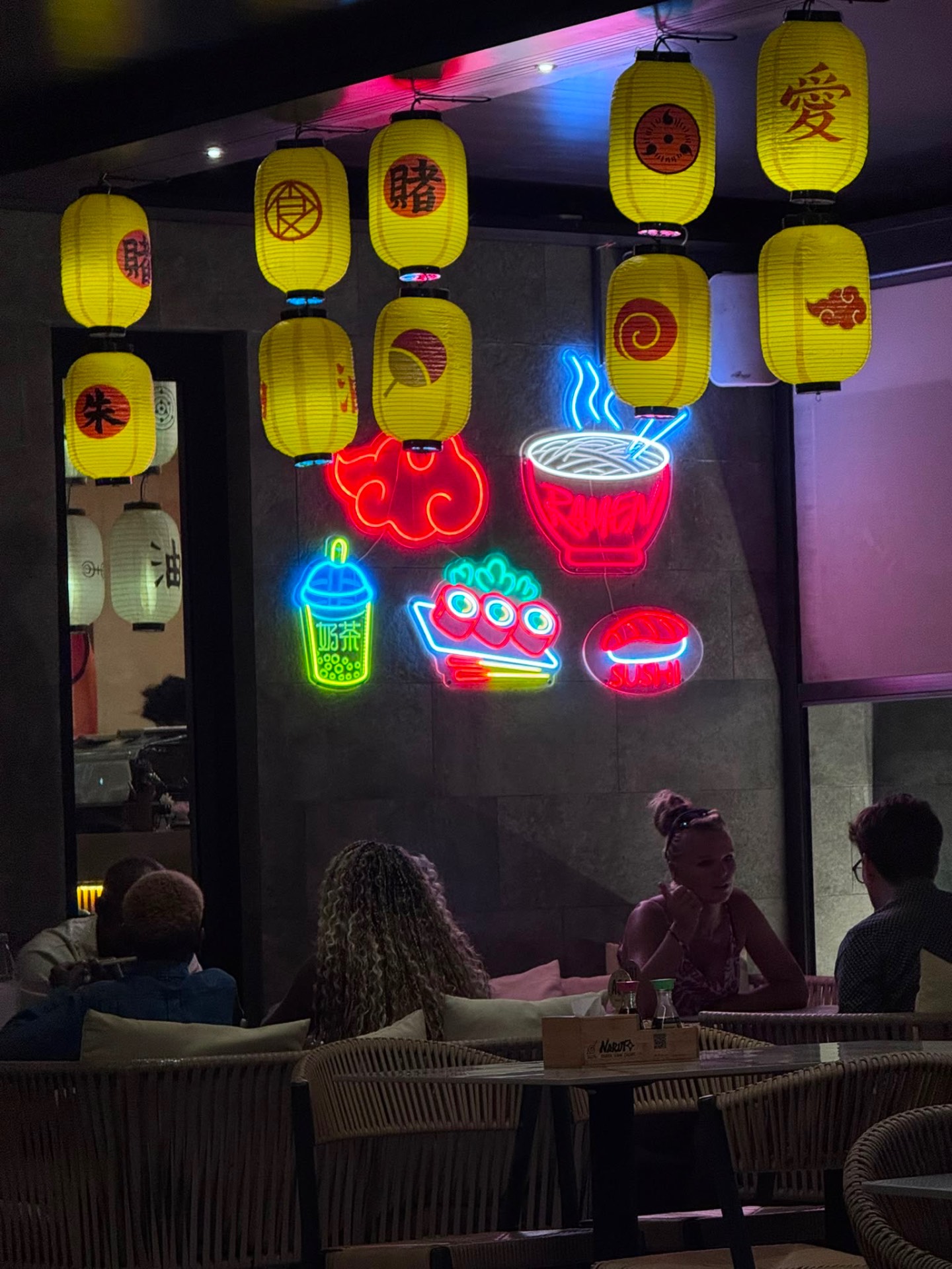 Neon ramen, sushi and boba signs with yellow lanterns inside Naruto SXM