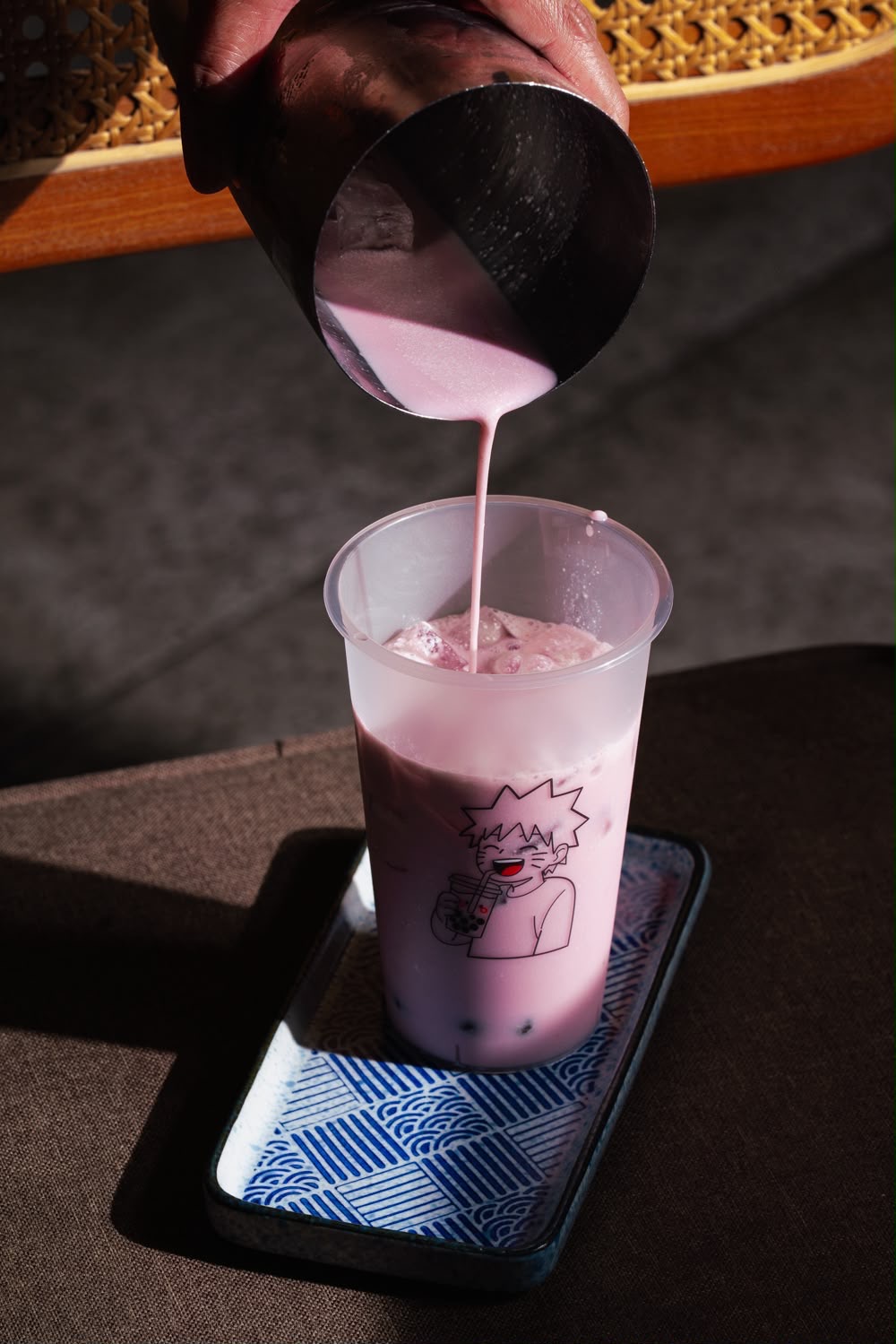 Taro milk being poured into a Naruto bubble tea cup